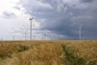 Windmills on field against sky