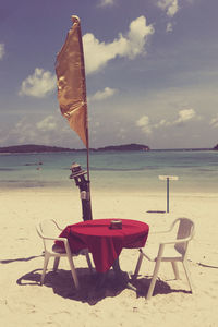 Deck chairs on beach against sky