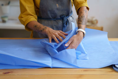 Self employed ceramist woman wrapping ceramics in protective paper preparing product for delivery