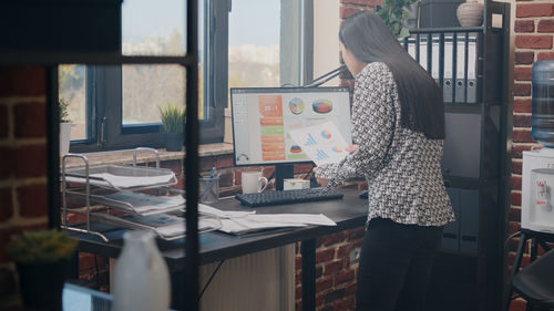 Side view of woman standing by window