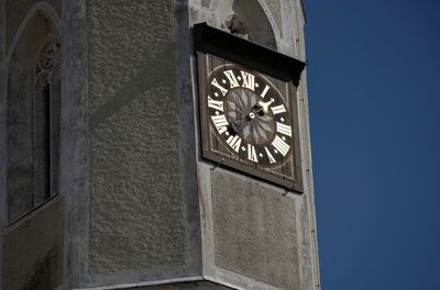 Low angle view of clock tower against clear blue sky on sunny day