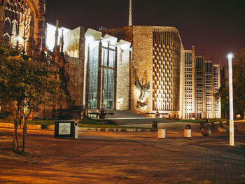 Illuminated building by street against sky at night