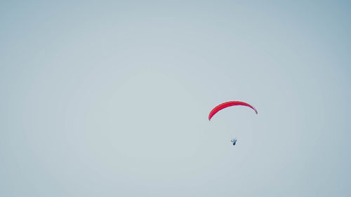 Low angle view of person paragliding against clear sky