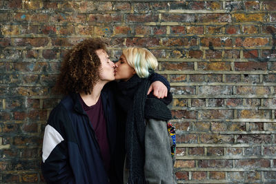 Young couple standing against brick wall