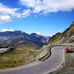 Road by mountains against sky