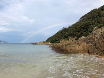 Scenic view of rainbow over sea and mountains