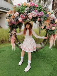 Portrait of woman standing by pink flowering plants