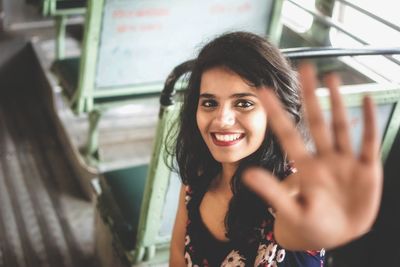 Portrait of smiling young woman gesturing while sitting in bus