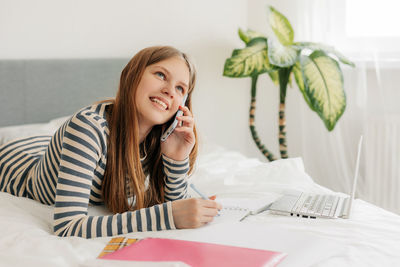 A student girl is talking on the phone, discussing homework with classmates. modern technologies