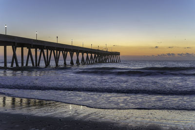 Pier over sea against sky during sunset