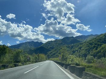 Empty road by mountains against sky