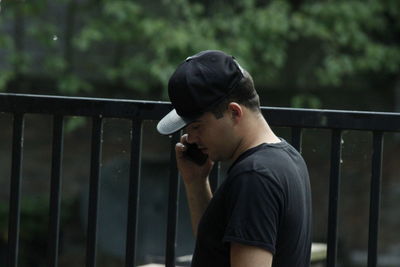 Man talking on smart phone while standing by railing