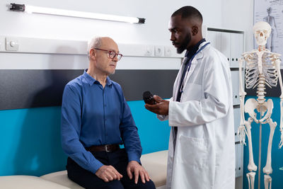 Doctor showing medicine bottle to patient in clinic