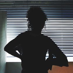 Rear view of silhouette woman standing at home