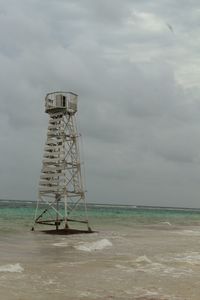 Lifeguard tower on beach against sky