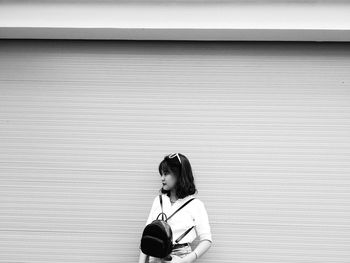 Young woman standing against wall