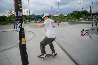 Rear view of man skateboarding on road in city