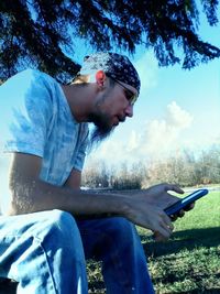 Side view of man sitting against sky