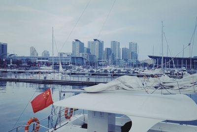Sailboats moored in harbor against buildings in city