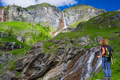 Rear view of woman on rock by waterfall