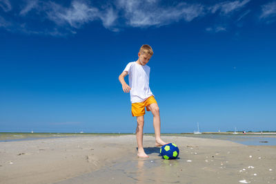 Full length of woman on beach against blue sky