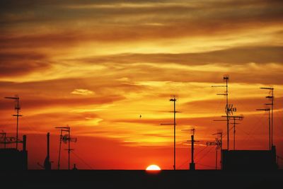 Silhouette antennas on building terrace at sunset