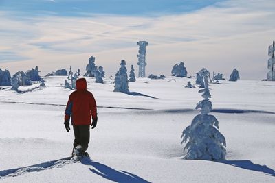 Rear view of boy walking on snowy landscape during winter