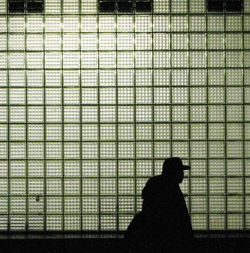 Silhouette man standing against window