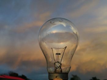 Low angle view of illuminated light bulb against sky