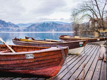 Boats moored on lake against sky