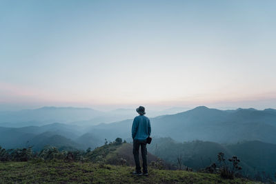 Rear view of man standing on mountain against sky