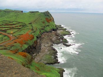 Scenic view of sea by cliff against sky