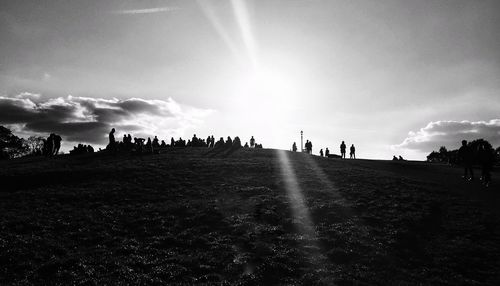 Silhouette people on landscape against sky