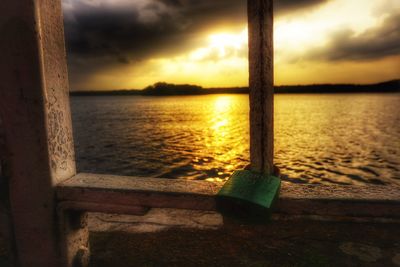 Close-up of tree trunk against sea during sunset