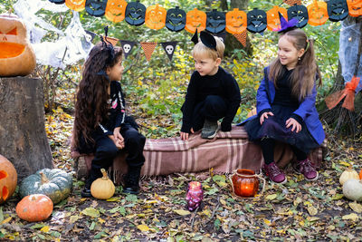 Happy kids in halloween costumes having fun in halloween decorations outdoor