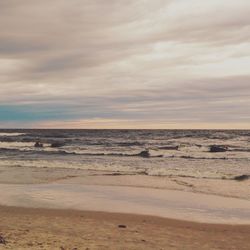 Scenic view of beach against cloudy sky