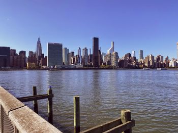 Sea by buildings in city against clear sky