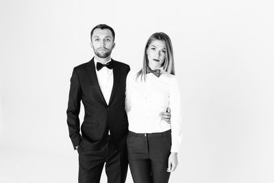 Portrait of confident elegant couple standing against white background