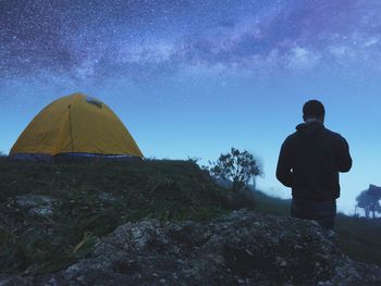 Rear view of man standing at campsite during night