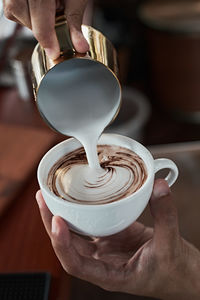 Midsection of person pouring coffee in cup