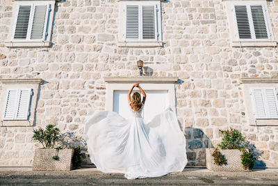 Midsection of woman standing against white wall of building