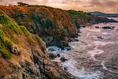 Scenic view of rocky mountains by sea against sky