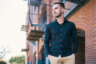 Low angle view of young man looking away standing outdoors