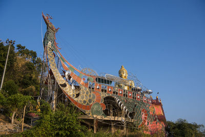 Low angle view of amusement park against clear blue sky