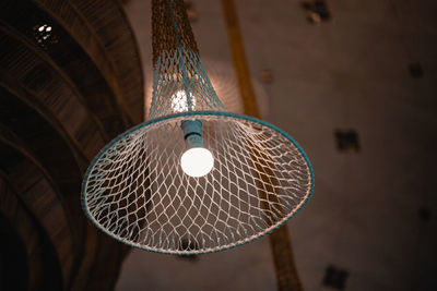 Low angle view of illuminated pendant light hanging on ceiling