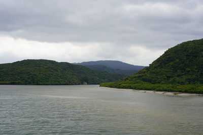 Scenic view of river by mountains against sky