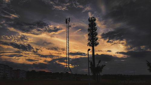 Silhouette trees on field against dramatic sky during sunset