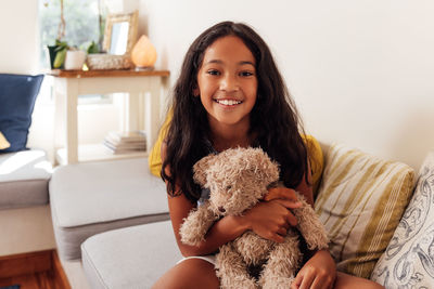 Portrait of young woman with teddy bear at home