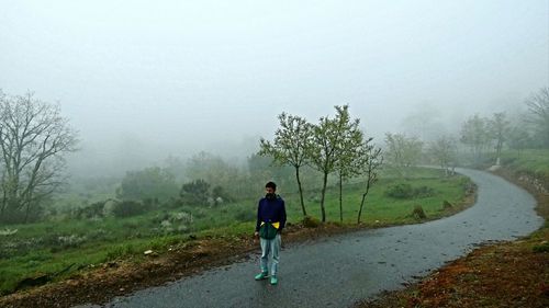 Rear view of man on road amidst trees