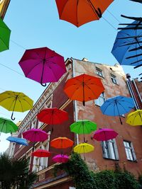 Low angle view of multi colored umbrellas hanging against sky